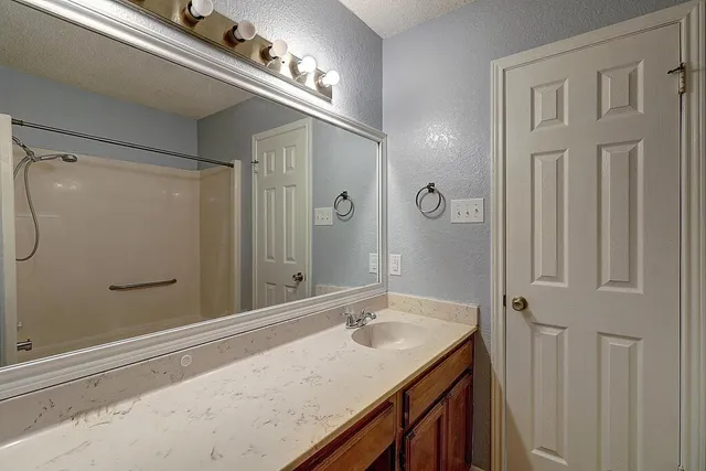 a bathroom with a granite countertop sink a mirror and a shower