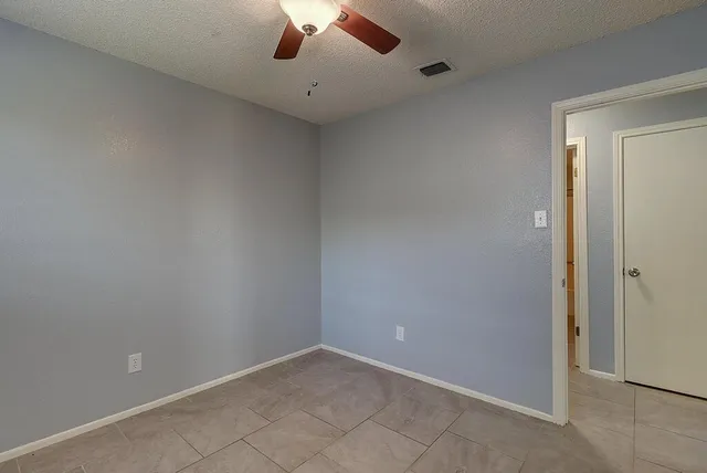 an empty room with a ceiling fan and carpet