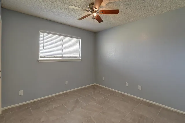 en empty room with windows and ceiling fan