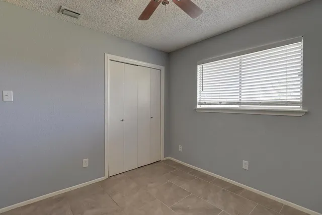 an empty room with a window and a ceiling fan