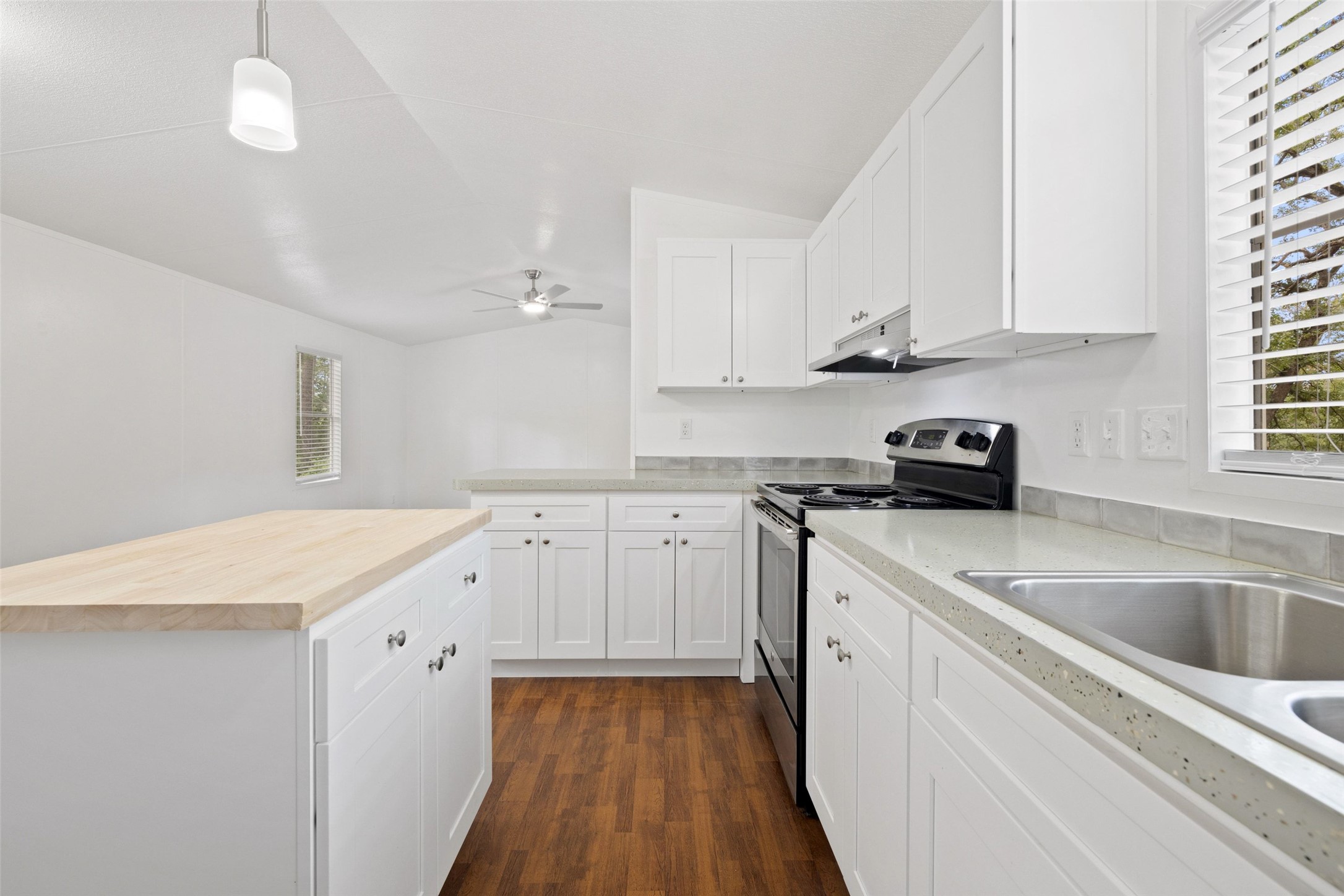 301 Porter Road, Unit A Bastrop, TX 78602 - Photo 6 of 28 a kitchen with granite countertop a sink dishwasher a stove and white cabinets with wooden floor