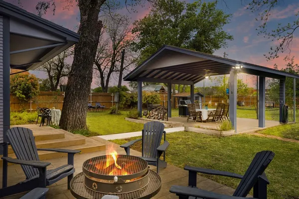 a view of a patio with table and chairs potted plants and large tree