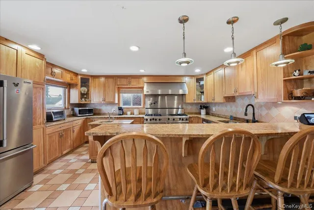 a kitchen with stainless steel appliances granite countertop a sink a stove a refrigerator and cabinets