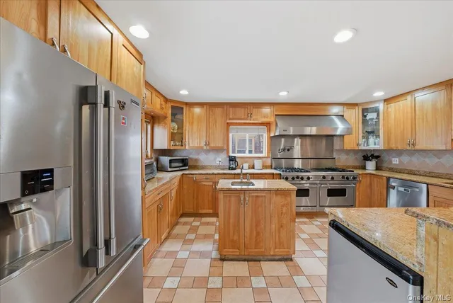 a kitchen with stainless steel appliances granite countertop a refrigerator a stove a sink and a microwave