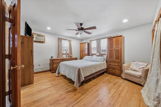 a bedroom with a bed and a ceiling fan with wooden floor