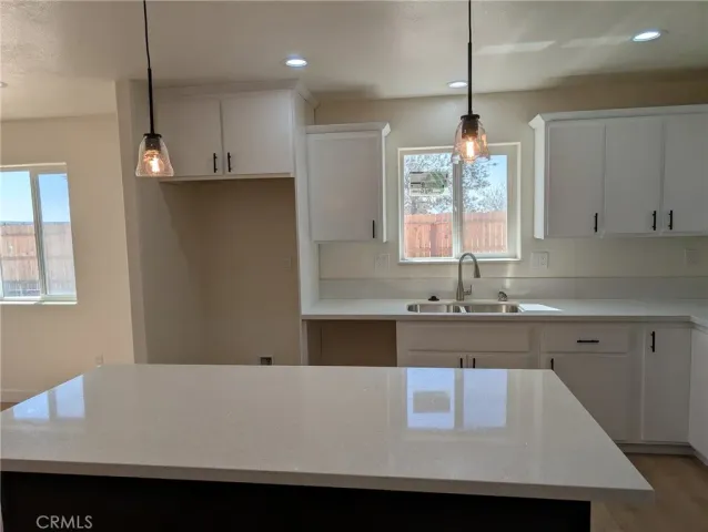 a kitchen with kitchen island a sink dishwasher a stove and white countertops with wooden floor