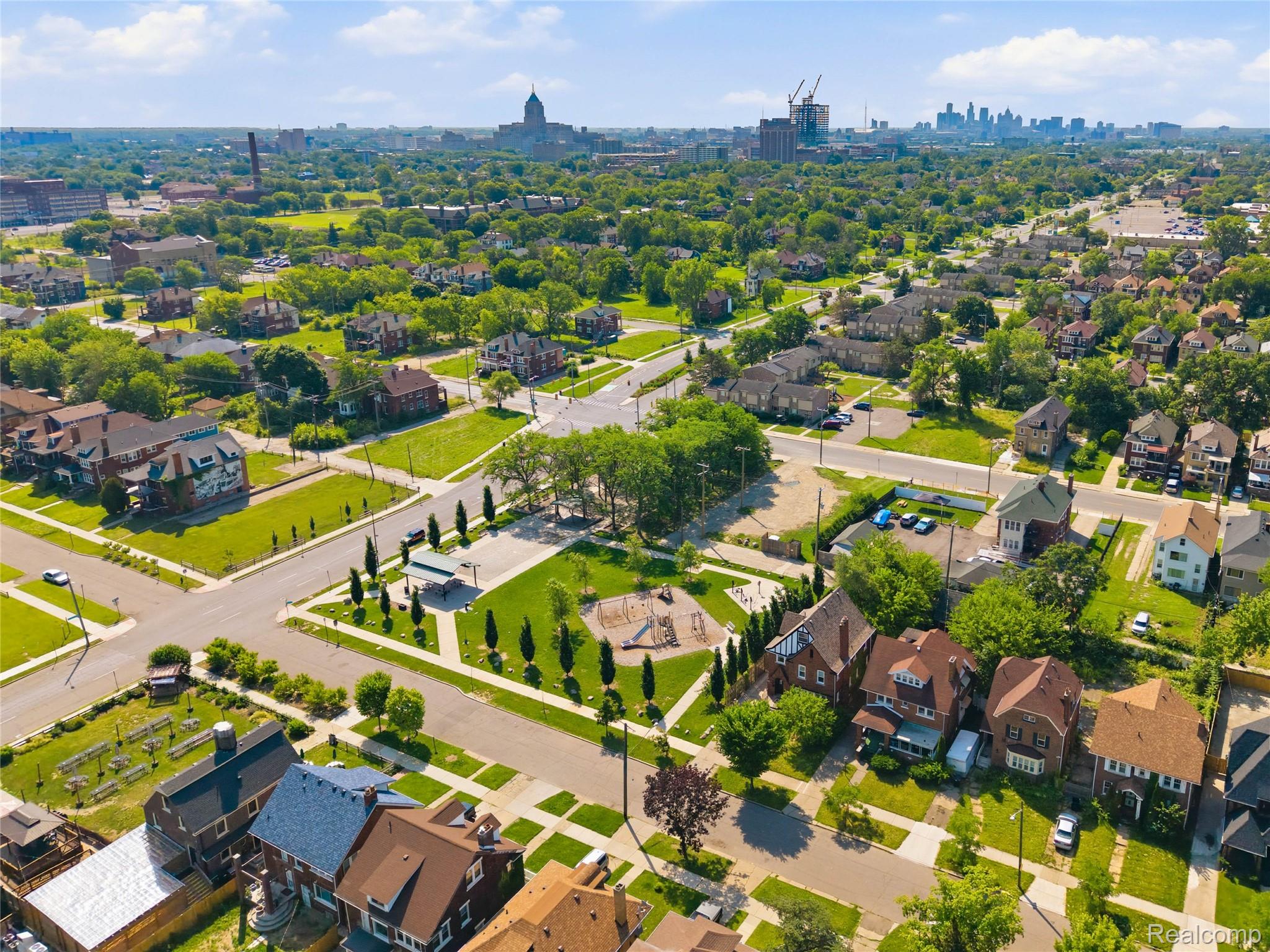 1945 Atkinson Street Detroit, MI 48206 - Photo 5 of 49 Aerial perspective showcasing a residential neighborhood with a variety of architectural styles, mature trees, and a central park space featuring a playground