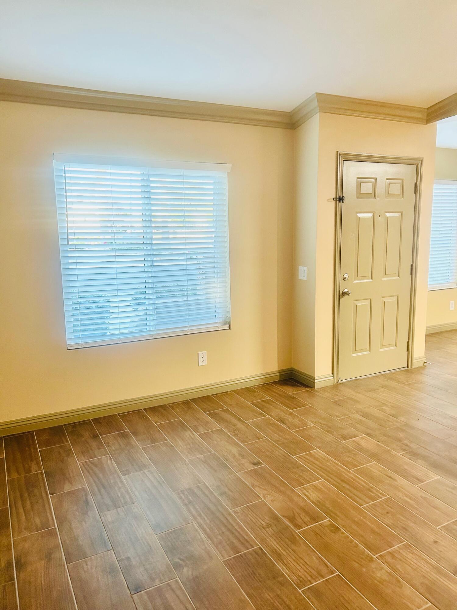 40780 Breezy Pass Road, Unit B Palm Desert, CA 92211 - Photo 13 of 32 a view of an empty room with wooden floor and a window