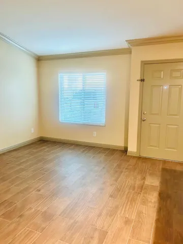 a view of an empty room with wooden floor and a window