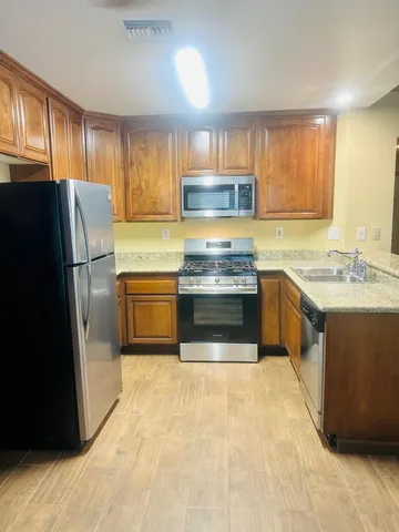 a kitchen with stainless steel appliances granite countertop a refrigerator a sink a stove a microwave and island