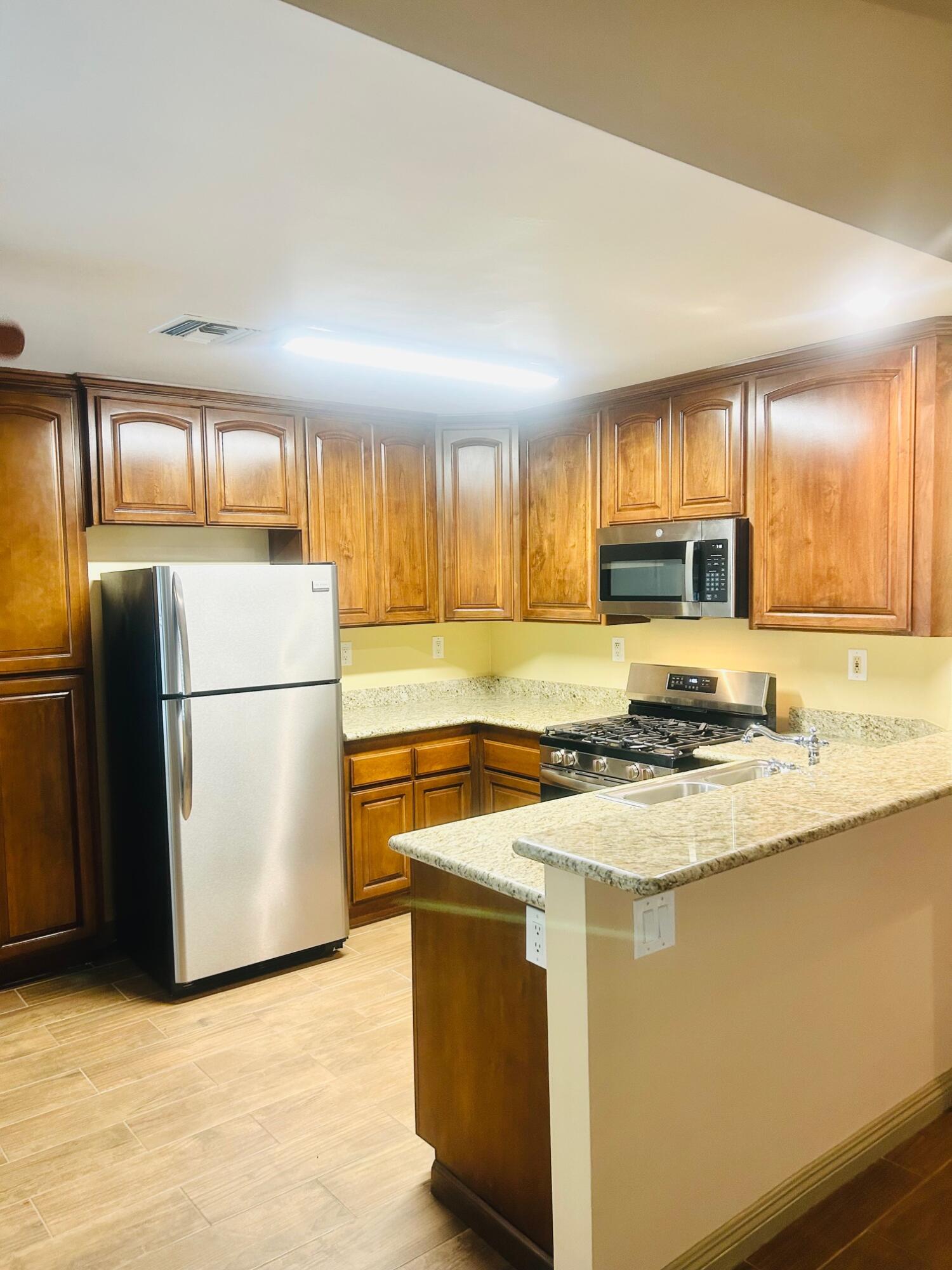 40780 Breezy Pass Road, Unit B Palm Desert, CA 92211 - Photo 7 of 32 a kitchen with stainless steel appliances granite countertop a refrigerator a stove a sink dishwasher and a refrigerator
