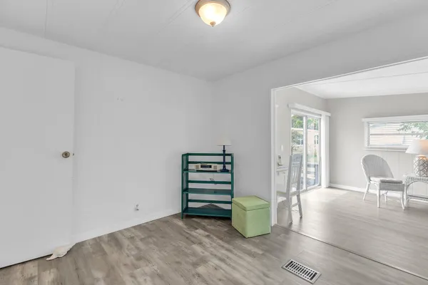 a view of an empty room with wooden floor and windows