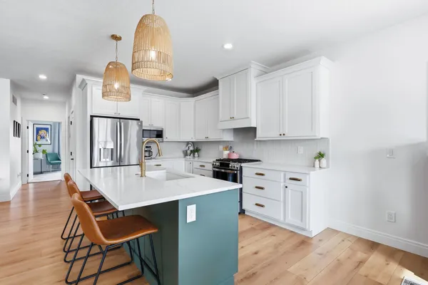 a kitchen with stainless steel appliances granite countertop a sink a stove a refrigerator cabinets and a dining table