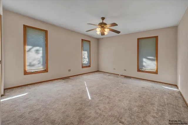 an empty room with windows and fan