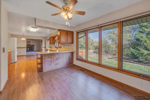 a large kitchen with stainless steel appliances granite countertop a stove and a view of living room with wooden floor