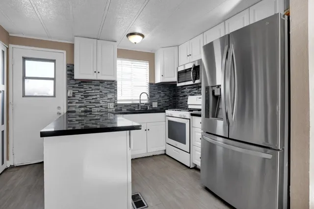 a kitchen with granite countertop a refrigerator stove and sink
