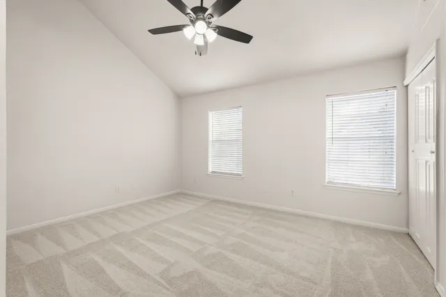 an empty room with windows and fan