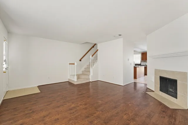 a view of an empty room with wooden floor and a fireplace