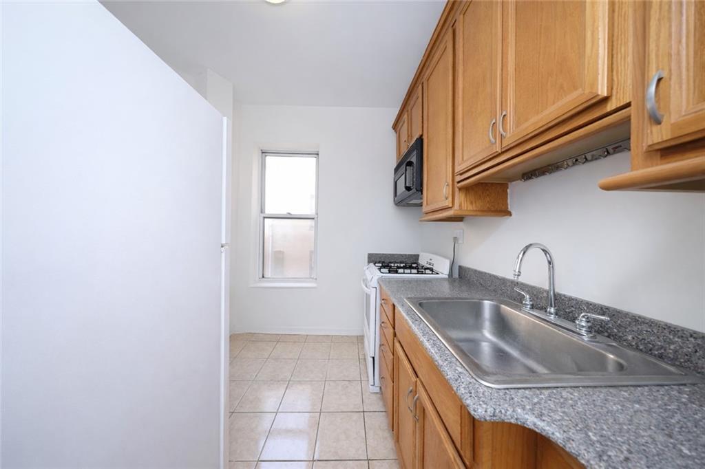 1489 East 8th Street, Unit C2 Brooklyn, NY 11230 - Photo 7 of 15 a kitchen with granite countertop a sink a stove and cabinets