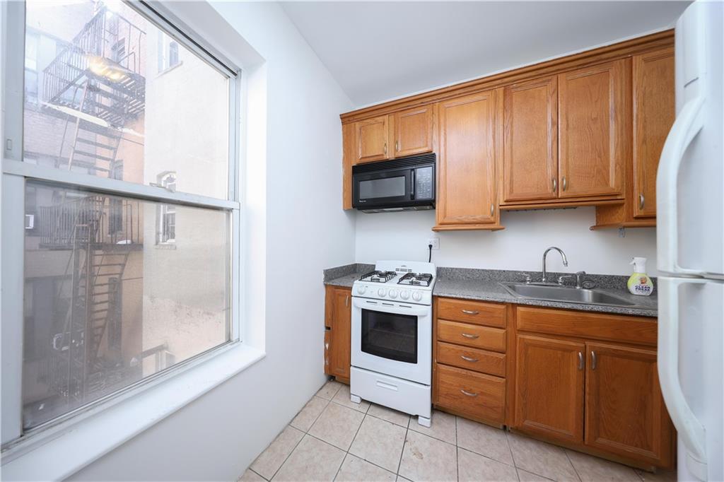 1489 East 8th Street, Unit C2 Brooklyn, NY 11230 - Photo 9 of 15 a kitchen with stainless steel appliances granite countertop a stove a sink and a microwave
