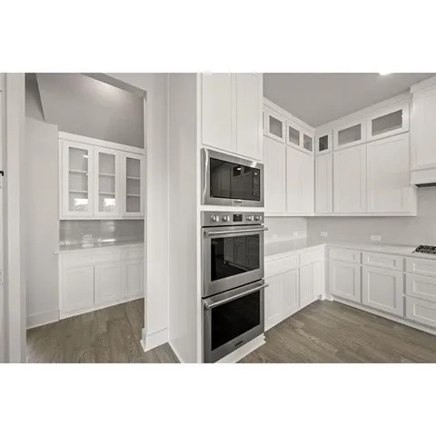 a view of a hallway with wooden floor and a bathroom