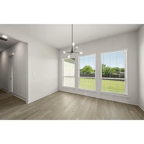 a view of a hallway with wooden floor and a chandelier fan