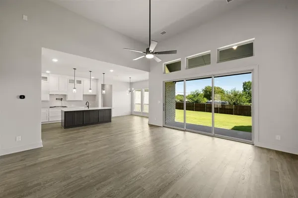 a kitchen with stainless steel appliances kitchen island granite countertop a sink a microwave a stove and a refrigerator with wooden floor