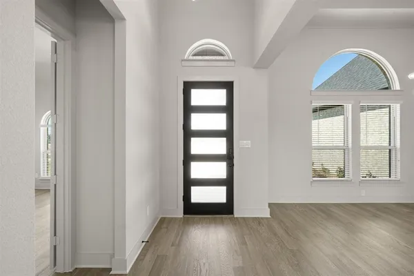 an empty room with wooden floor cabinet and windows