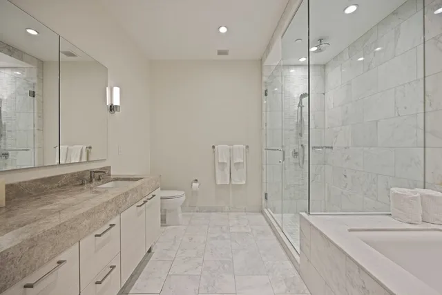 a spacious bathroom with a granite countertop sink a toilet a mirror and shower
