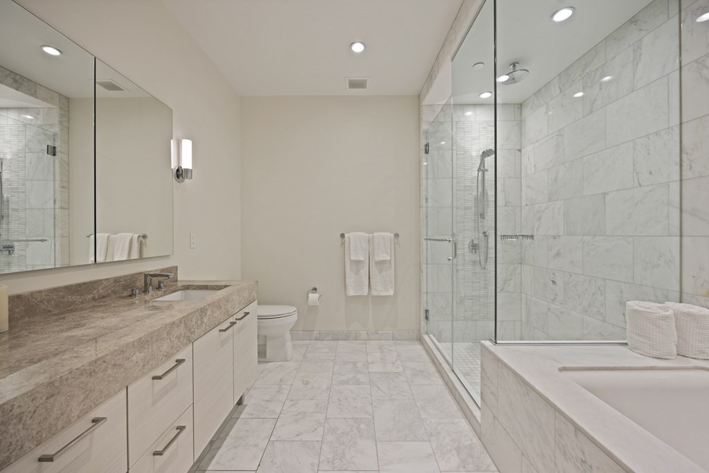 1 Franklin Street, Unit 5204 Boston, MA 02110 - Photo 21 of 40 a spacious bathroom with a granite countertop sink a toilet a mirror and shower