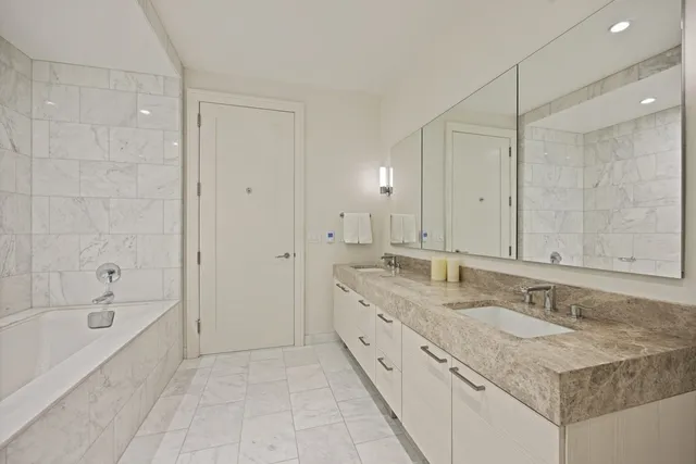 a bathroom with a granite countertop sink mirror and a bathtub