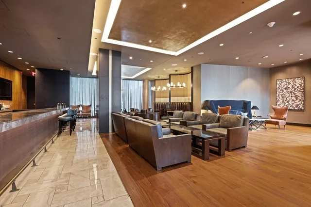 a living room with furniture a wooden floor and a view of kitchen