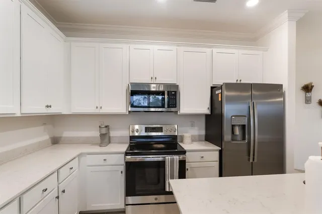 a kitchen with a refrigerator sink and white cabinets