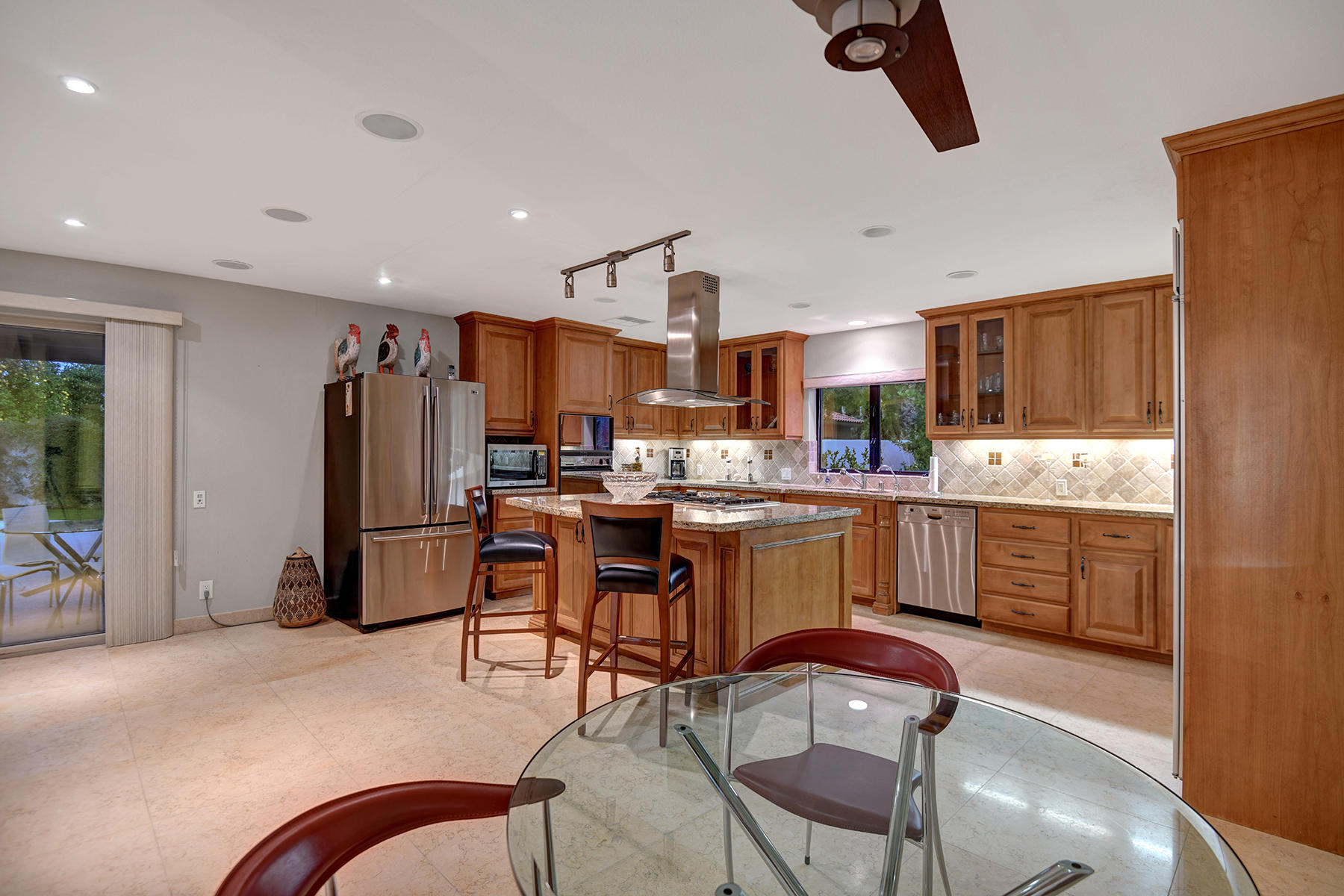 4 Boothill Circle Rancho Mirage, CA 92270 - Photo 42 of 55 a kitchen with stainless steel appliances kitchen island granite countertop a refrigerator a stove a sink a dining table and chairs with wooden floor
