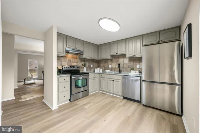 a kitchen with a refrigerator cabinets and wooden floor