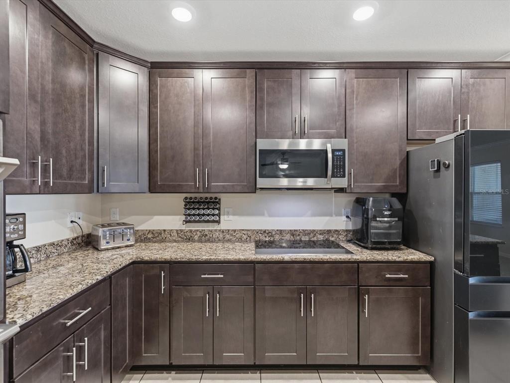 13169 Santee Street Spring Hill, FL 34609 - Photo 14 of 58 a kitchen with kitchen island granite countertop stainless steel appliances a sink stove refrigerator and cabinets
