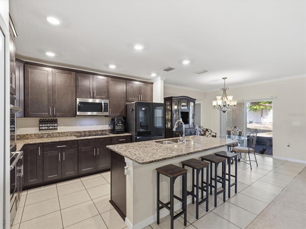 13169 Santee Street Spring Hill, FL 34609 - Photo 17 of 58 a kitchen with granite countertop a center island a sink stainless steel appliances and cabinets