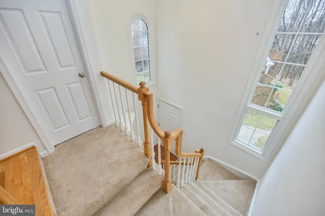 a view of staircase with white walls and lots of frames on wall