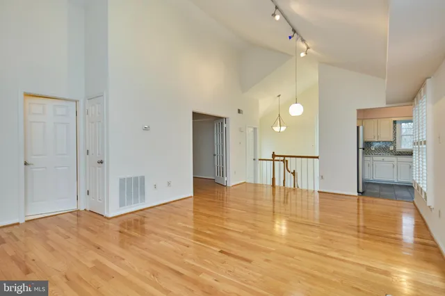 a view of an empty room with wooden floor and a bathroom