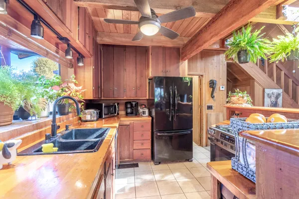 a kitchen with stainless steel appliances granite countertop a refrigerator a stove and a sink with wooden floor