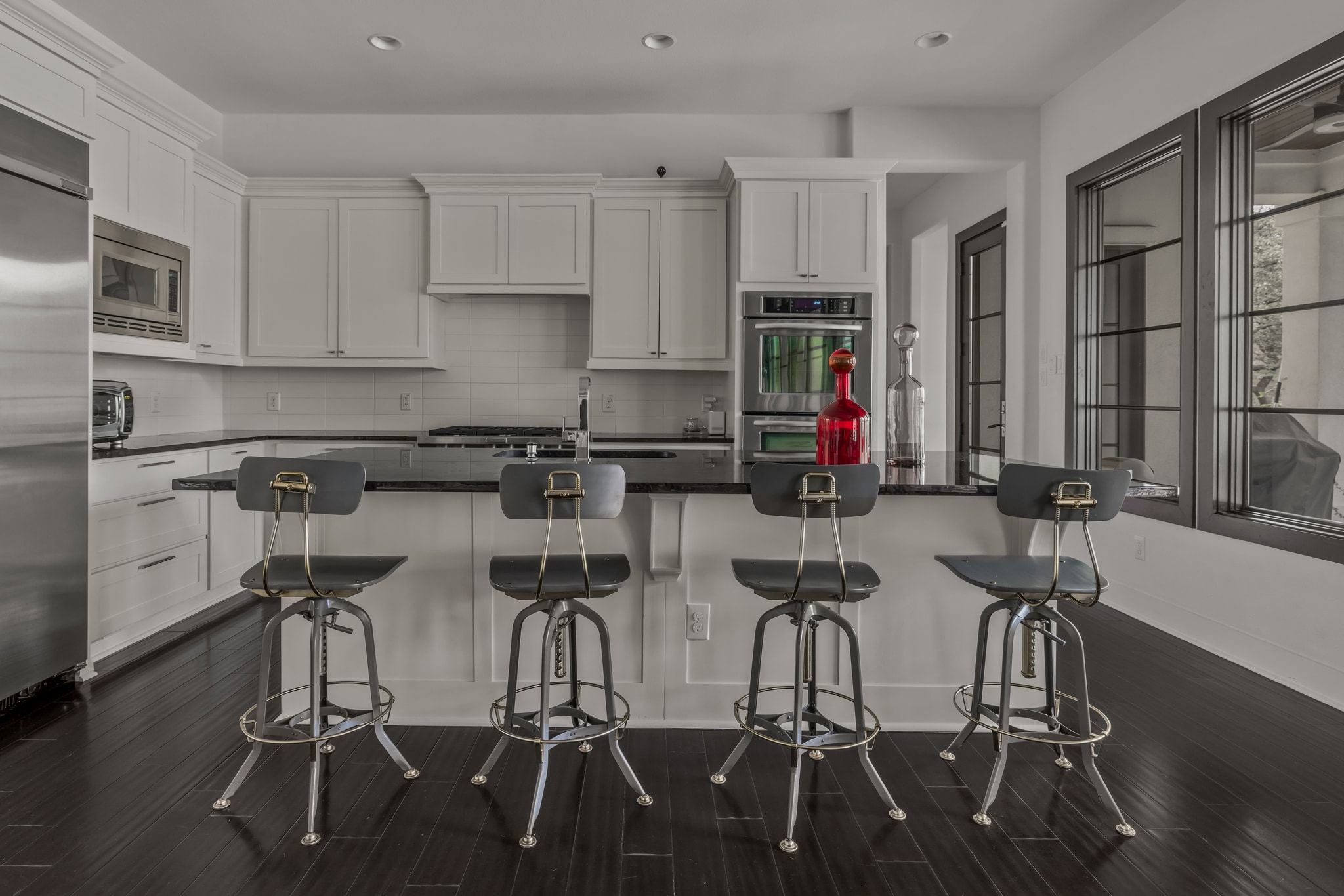 4720 Rockcliff Road, Unit 1 Austin, TX 78746 - Photo 15 of 39 A sleek kitchen boasts dark hardwood floors, white cabinetry, and a generously sized island with seating.