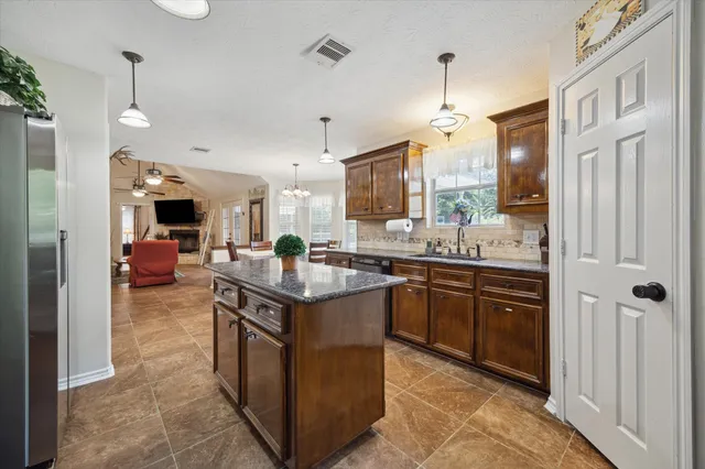 a kitchen with stainless steel appliances granite countertop a sink and a refrigerator