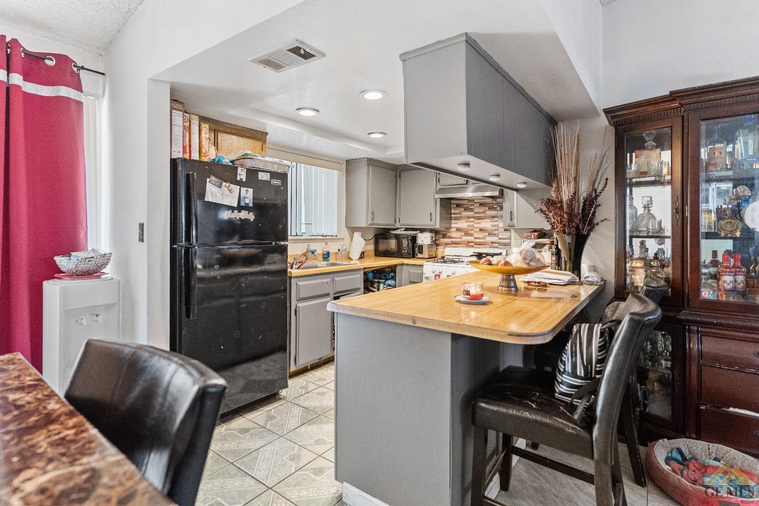 Undisclosed Address Bakersfield, CA 93304 - Photo 11 of 19 a kitchen with stainless steel appliances kitchen island granite countertop a refrigerator a sink a stove and chairs with wooden floor