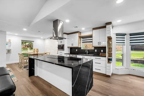 a kitchen with stainless steel appliances a sink a stove a refrigerator cabinets and living room view