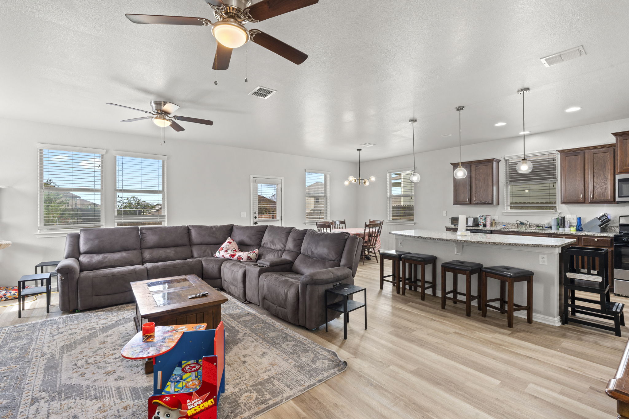 424 Wapiti Road Buda, TX 78610 - Photo 5 of 21 An inviting open-concept living area boasts light-toned flooring and abundant natural light, flowing seamlessly into a kitchen with a spacious island.
