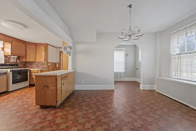 a kitchen with stainless steel appliances granite countertop a stove a sink dishwasher a refrigerator and white cabinets with wooden floor