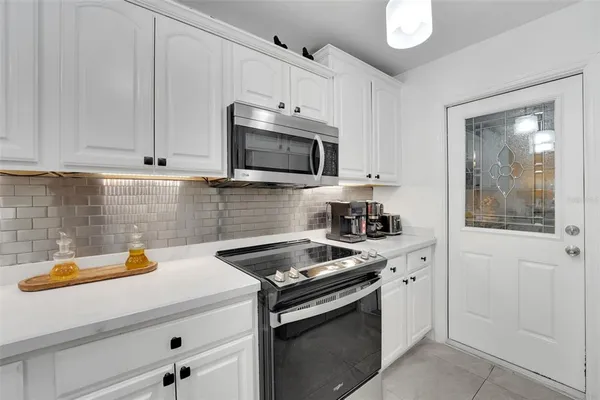 a kitchen with stainless steel appliances a white stove top oven and white cabinets