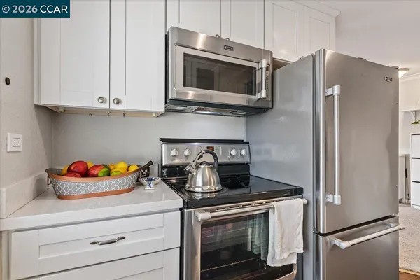 a kitchen with stainless steel appliances white cabinets white stove a microwave and a refrigerator