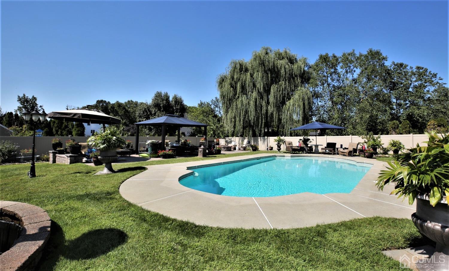1 MacFarlane Circle Monroe Township, NJ 08831 - Photo 15 of 26 a view of a swimming pool with lawn chairs under an umbrella