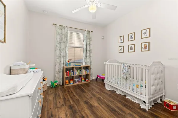 a bedroom with baby crib and a wooden floor